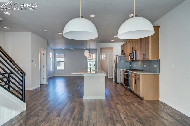 kitchen featuring stainless steel appliances, dark hardwood / wood-style floors, an island with sink, decorative light fixtures, and decorative backsplash