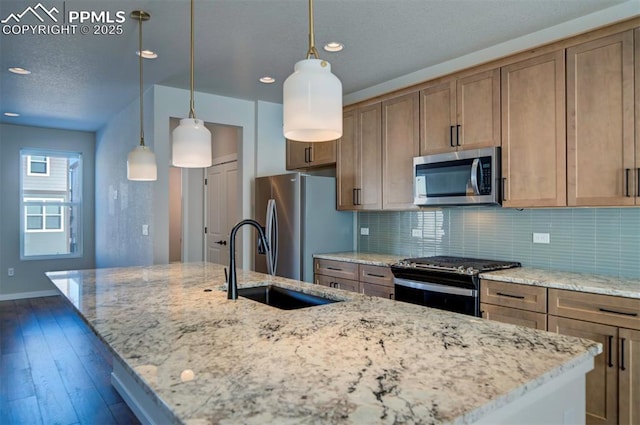 kitchen featuring light stone countertops, pendant lighting, an island with sink, and stainless steel appliances