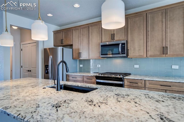 kitchen with sink, tasteful backsplash, decorative light fixtures, light stone counters, and stainless steel appliances