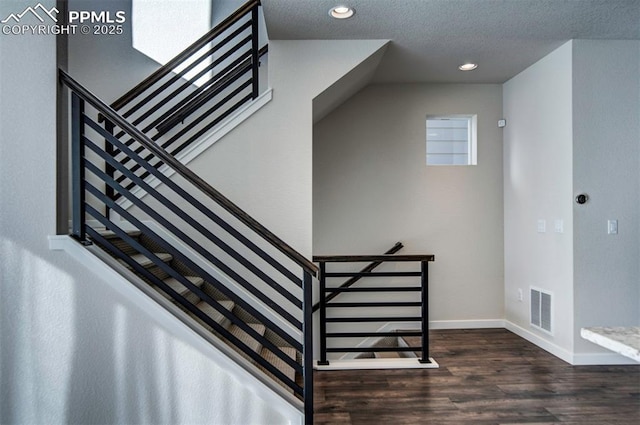 stairway with a textured ceiling and hardwood / wood-style flooring