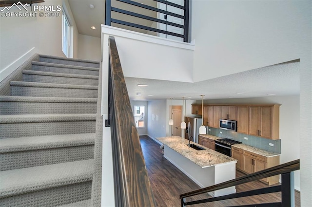 stairway with wood-type flooring, a towering ceiling, and sink