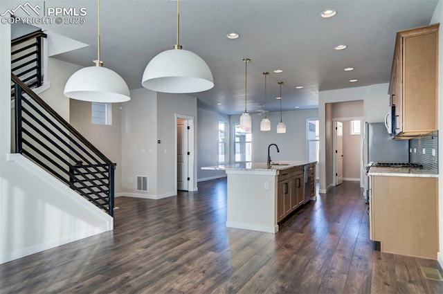 kitchen featuring light stone countertops, dark wood-type flooring, wine cooler, pendant lighting, and a center island with sink