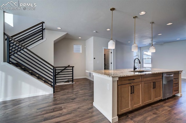 kitchen with sink, hanging light fixtures, light stone counters, dark hardwood / wood-style flooring, and an island with sink