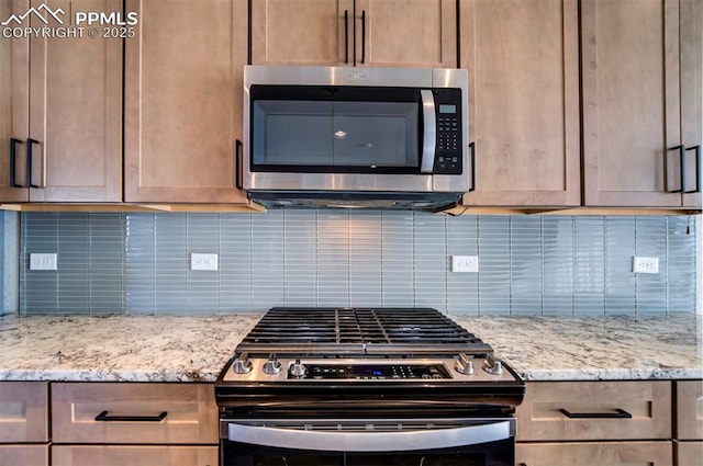 kitchen with light stone counters, appliances with stainless steel finishes, and tasteful backsplash