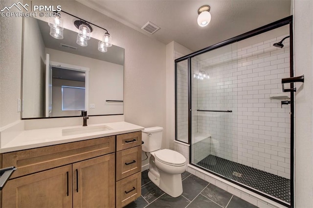 bathroom featuring tile patterned flooring, vanity, toilet, and a shower with door