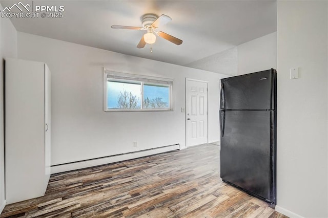 kitchen featuring ceiling fan, black refrigerator, wood-type flooring, and a baseboard heating unit