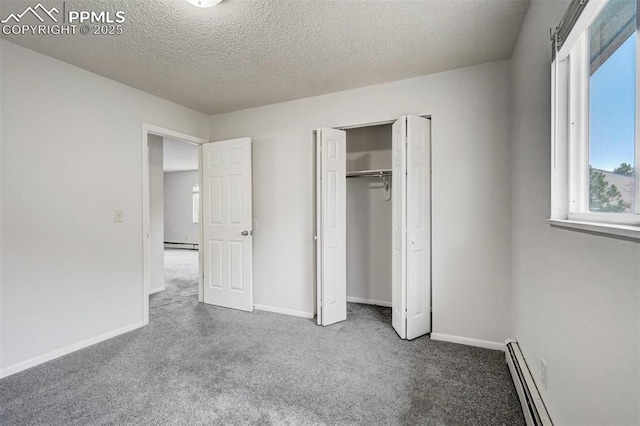 unfurnished bedroom featuring a closet, carpet floors, a textured ceiling, and a baseboard heating unit