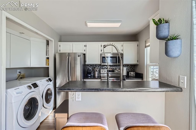 kitchen featuring white cabinetry, appliances with stainless steel finishes, washer and clothes dryer, and tasteful backsplash