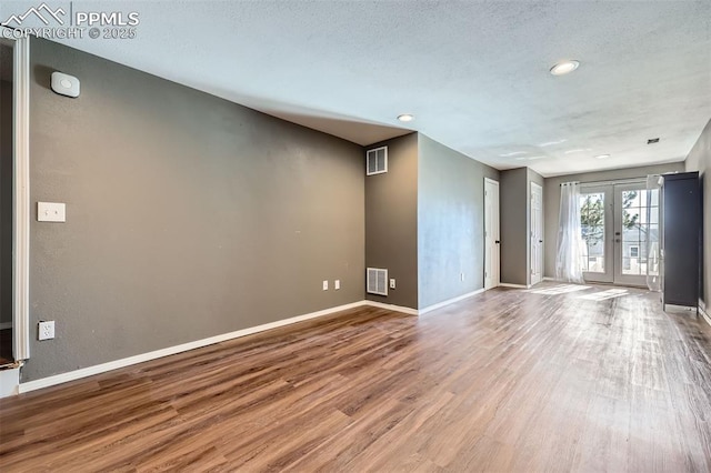 spare room with hardwood / wood-style floors, a textured ceiling, and french doors