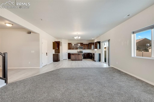 unfurnished living room featuring light carpet and an inviting chandelier