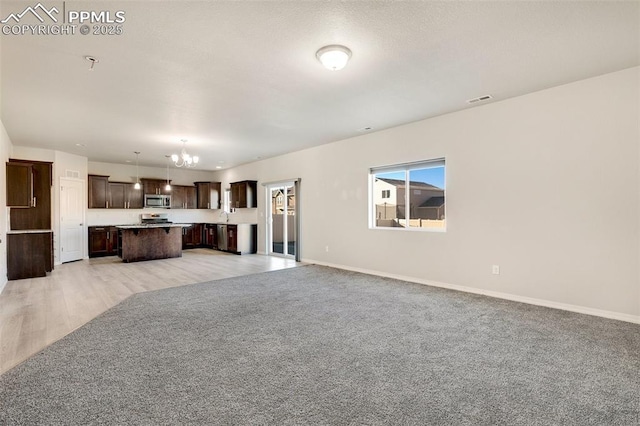 unfurnished living room featuring light colored carpet and a chandelier