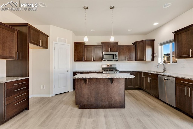 kitchen with dark brown cabinets, light wood-type flooring, hanging light fixtures, and appliances with stainless steel finishes