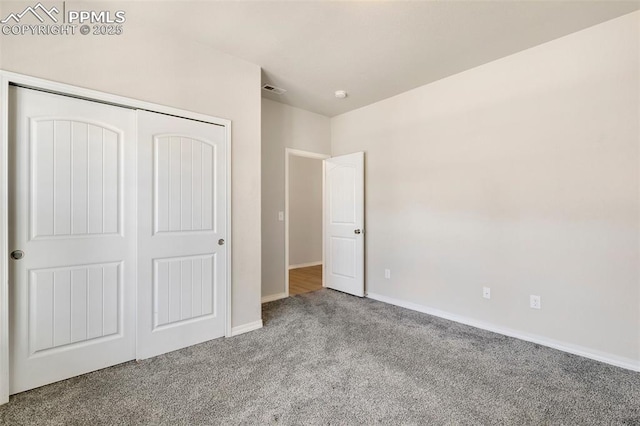 unfurnished bedroom with light colored carpet and a closet