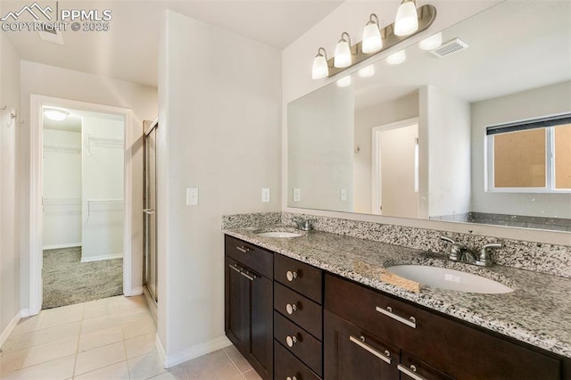 bathroom with tile patterned flooring, vanity, and walk in shower