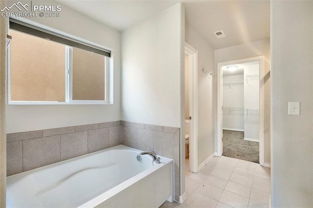 bathroom with tile patterned flooring, toilet, and a tub