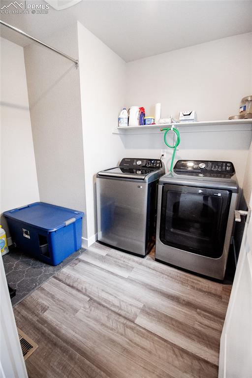 washroom with hardwood / wood-style flooring and separate washer and dryer