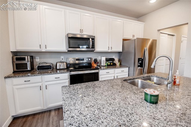 kitchen with light stone countertops, white cabinetry, sink, and stainless steel appliances