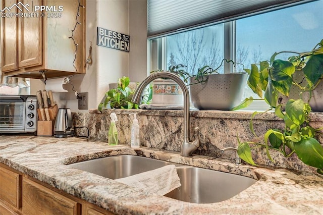 kitchen featuring sink and light stone countertops