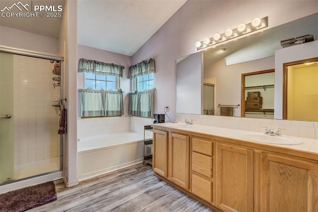 bathroom featuring vanity, hardwood / wood-style flooring, vaulted ceiling, and independent shower and bath