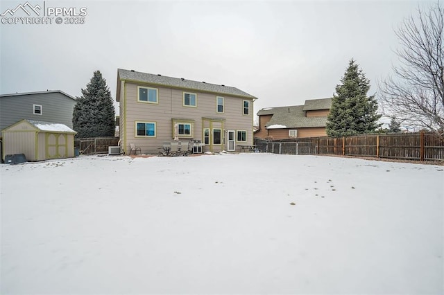 snow covered house with a shed and central air condition unit