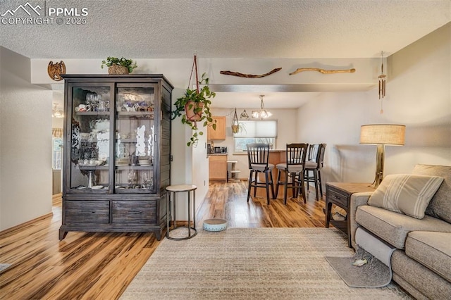 living room with hardwood / wood-style floors, a notable chandelier, and a textured ceiling