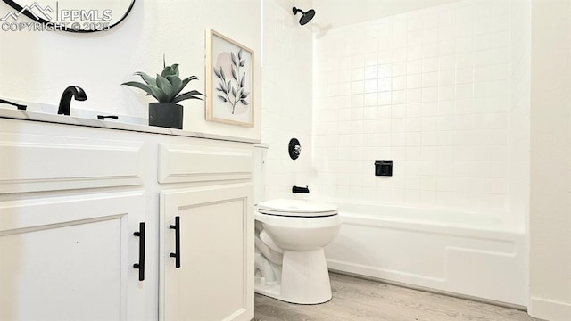 full bathroom with hardwood / wood-style flooring, toilet, washtub / shower combination, and sink