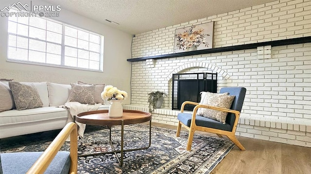 living area featuring hardwood / wood-style floors, brick wall, and a textured ceiling