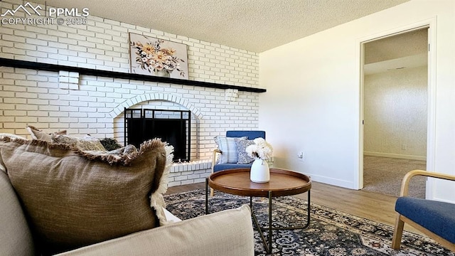 living area featuring a textured ceiling, hardwood / wood-style flooring, and a brick fireplace