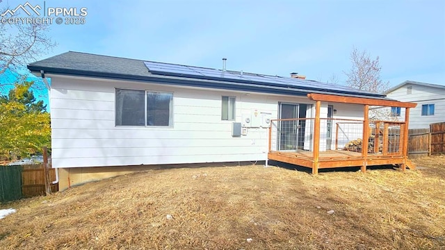 rear view of property with solar panels and a wooden deck