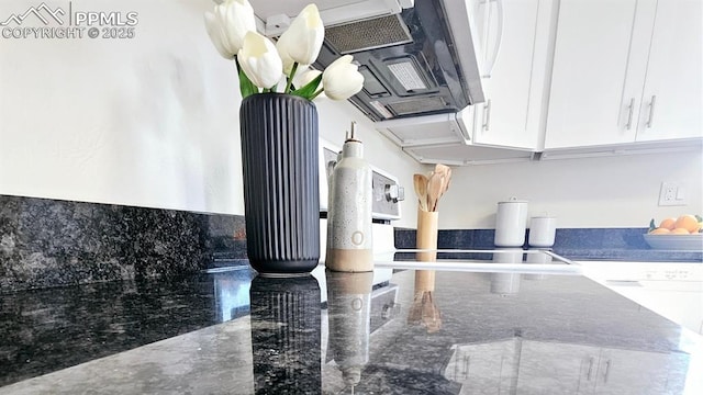 details featuring white cabinets, dishwashing machine, and dark stone counters