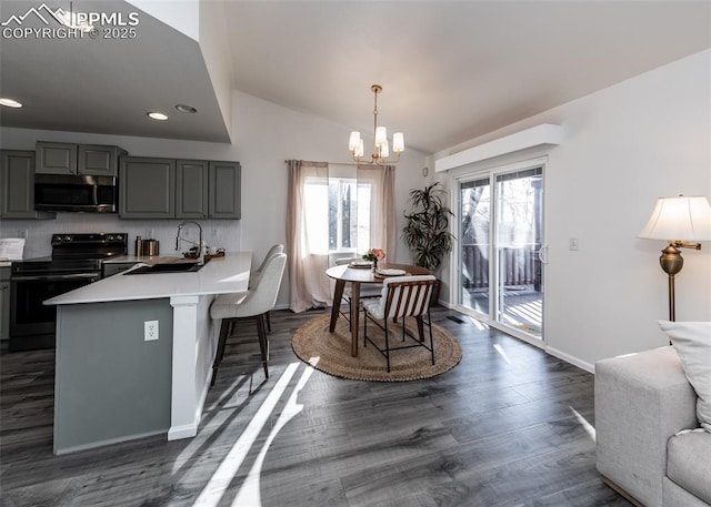 kitchen featuring electric range, sink, a kitchen breakfast bar, kitchen peninsula, and vaulted ceiling