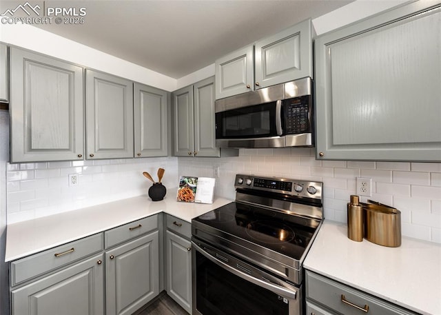 kitchen with backsplash, stainless steel appliances, and gray cabinets