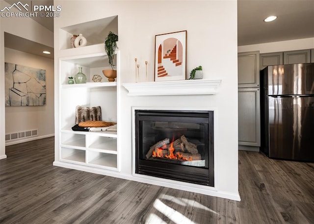 details with stainless steel fridge, built in features, and hardwood / wood-style flooring