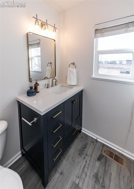 bathroom featuring wood-type flooring, vanity, toilet, and a wealth of natural light