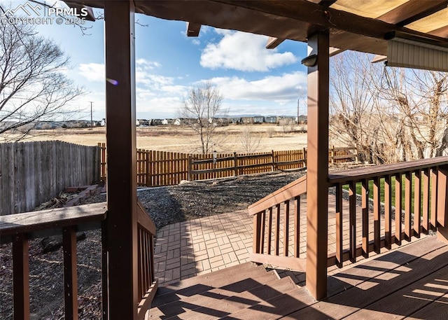 wooden terrace with a rural view and a patio