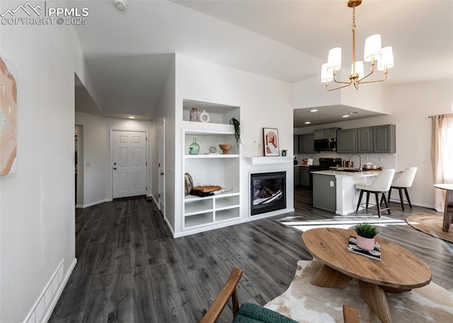 living room with built in shelves, dark hardwood / wood-style floors, and an inviting chandelier