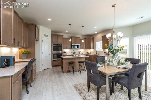 dining space featuring light wood-type flooring, an inviting chandelier, and sink