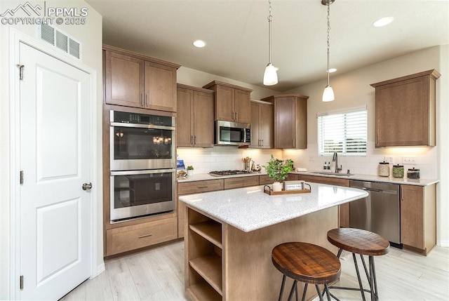 kitchen featuring a center island, sink, stainless steel appliances, light hardwood / wood-style flooring, and pendant lighting