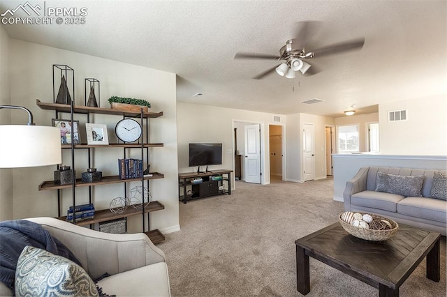 carpeted living room with ceiling fan and a textured ceiling