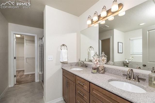 bathroom featuring vanity, an enclosed shower, and a textured ceiling