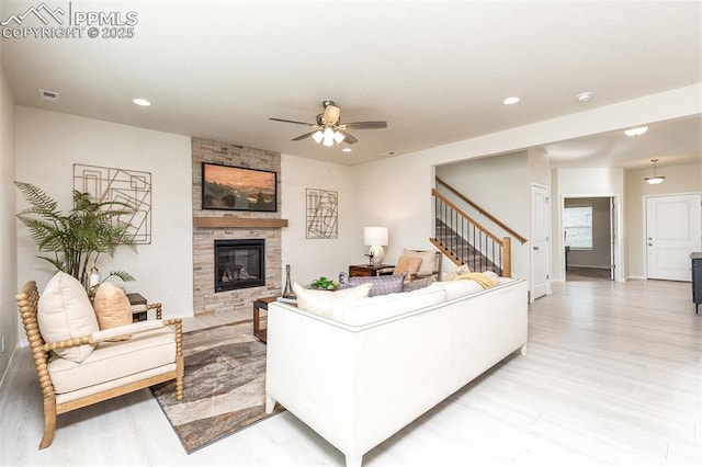 living room featuring ceiling fan, a fireplace, and light hardwood / wood-style flooring