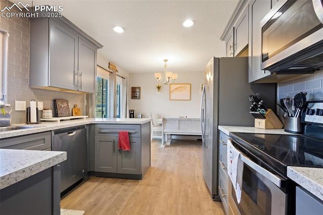 kitchen featuring decorative light fixtures, backsplash, appliances with stainless steel finishes, and gray cabinets