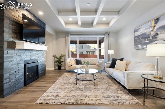 living room with coffered ceiling, wood-type flooring, a tiled fireplace, and beamed ceiling