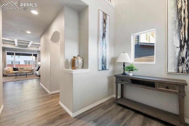 hall with beam ceiling, coffered ceiling, and hardwood / wood-style floors