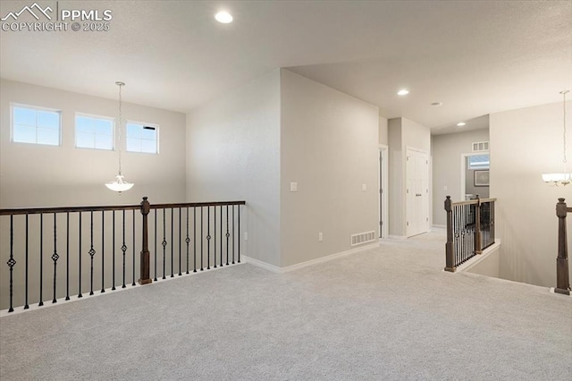 unfurnished room featuring an inviting chandelier and light colored carpet