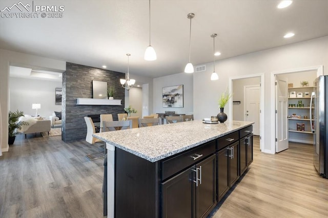 kitchen featuring light stone counters, a center island, light wood-type flooring, and hanging light fixtures