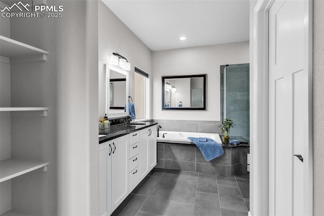 bathroom featuring tile patterned flooring, vanity, and a relaxing tiled tub