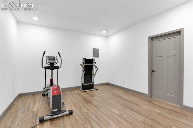 workout room with light hardwood / wood-style floors and electric panel