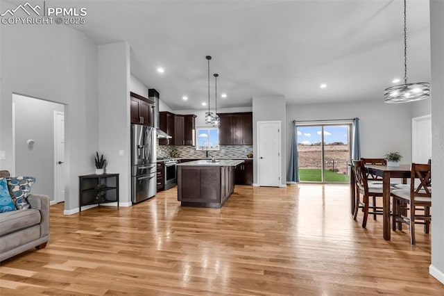 kitchen with dark brown cabinetry, stainless steel appliances, decorative light fixtures, decorative backsplash, and a kitchen island