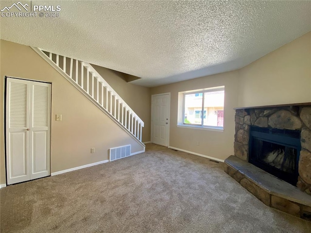 unfurnished living room with carpet flooring, a fireplace, and a textured ceiling